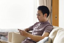 Adulte asiatique l'homme en utilisant smartphone à la maison — Photo de stock