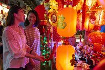 Young asian couple of friends spending time together on traditional bazaar at Chinese New Year — Stock Photo