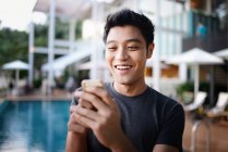Молода приваблива азіатка використовує смартфон проти басейну — стокове фото