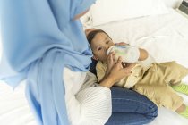 Junge asiatische muslimische Mutter mit Kind, Mutter füttert Baby mit Milchflasche — Stockfoto