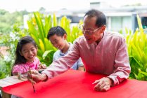 Heureux asiatique famille ensemble, grand-père et petits-enfants dessin hiéroglyphes — Photo de stock