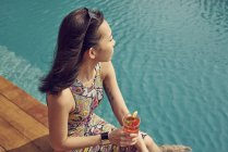 Bella giovane donna rilassante con bevanda vicino alla piscina — Foto stock