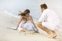 Glückliche junge Familie verbringt Zeit zusammen am Strand — Stockfoto