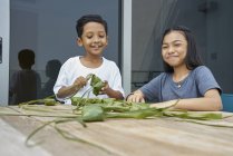 Jeunes frères et sœurs asiatiques célébrant Hari Raya ensemble à la maison et faisant des décorations — Photo de stock