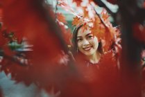 Счастливая красивая азиатская женщина портрет через осенние ветви деревьев — стоковое фото