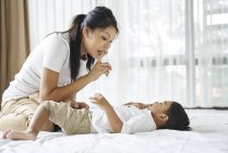 Азиатская мать связывается со своим сыном на кровати — стоковое фото