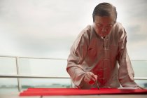 Старий азіатський чоловік малює ієрогліфи каліграфії на китайському новому році — стокове фото