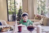 Счастливый мальчик в шляпе санта, празднующий Новый год за столом — стоковое фото
