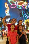 LIBERTAS Familia alegre tomando selfies en Hari Raya Geylang Bazaar, Singapur - foto de stock
