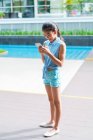 Giovane ragazza asiatica utilizzando smartphone in piscina — Foto stock