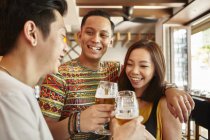 Feliz joven asiático amigos beber cerveza en bar - foto de stock