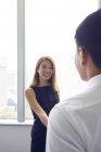 Молода азіатська бізнес-леді тремтить руками з чоловіком в сучасному офісі — стокове фото
