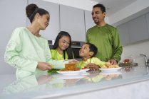 Giovane famiglia asiatica che celebra Hari Raya insieme a casa e cucina piatti tradizionali — Foto stock