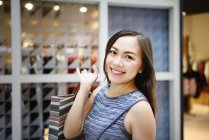 Щаслива красива азіатська жінка в магазині з сумкою — стокове фото