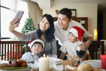 LIBERTAS Feliz familia asiática celebrando la Navidad juntos en casa y tomando selfie - foto de stock