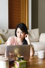 Молода випадкова азіатська жінка використовує ноутбук вдома — стокове фото