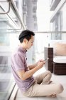 Взрослый азиатский мужчина, использующий смартфон дома — стоковое фото