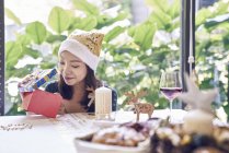 Feliz jovem asiático mulher celebrando natal e desembalagem presente — Fotografia de Stock
