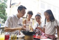 Glücklich asiatische Familie essen Nudeln zusammen in Straßencafé — Stockfoto