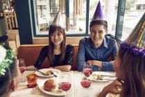 Счастливые молодые люди и их друзья вместе празднуют Новый год в кафе — стоковое фото