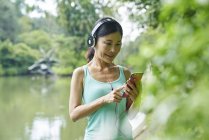 Porträt einer Frau mittleren Alters, die beim Spazierengehen in botanischen Gärten Musik hört — Stockfoto