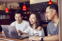 Heureux jeunes amis asiatiques ensemble travailler avec ordinateur portable dans bar — Photo de stock