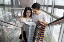 Young attractive asian couple together with shopping bags in mall — Stock Photo