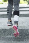 Image recadrée des jambes qui courent sur des marches en béton à l'extérieur . — Photo de stock
