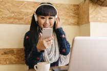 Молодая привлекательная азиатка, использующая смартфон в кафе — стоковое фото