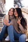 Chinese and european women taking a funny selfie sitting in a starway — Stock Photo