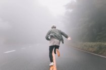 Visão traseira de um jovem hipster correndo na estrada no campo de Tóquio — Fotografia de Stock