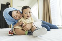 Молода азіатська мусульманська мати і дитина розважаються вдома — стокове фото