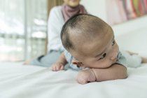 Nahaufnahme eines kleinen asiatischen Babys, das auf dem Bett liegt — Stockfoto