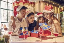 Happy young asian friends celebrating christmas together in cafe — Stock Photo