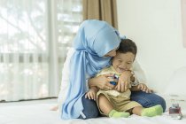 Молодая азиатская мусульманка мать и ребенок веселятся дома — стоковое фото