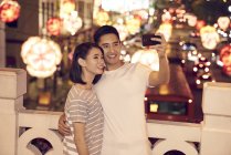 Jovem asiático casal passar tempo juntos no tradicional bazar no chinês ano novo e tomando selfie — Fotografia de Stock