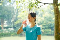 Mujer hidratante después de hacer ejercicio en Botanic Gardens, Singapur - foto de stock