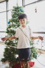 Щасливий азіатський хлопчик тримає різдвяну гірлянду вдома — стокове фото