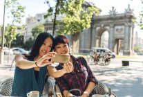 Japanische und chinesische Touristinnen machen Selfie auf einer Terrasse in der Nähe der Puerta de Alcala in Madrid, Spanien. — Stockfoto