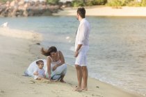 Счастливая молодая семья, проводящая время вместе на пляже — стоковое фото