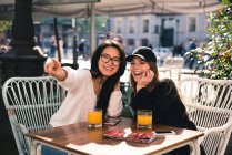 Two beautiful female friends in cafe pointing on something — Stock Photo