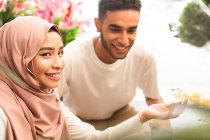 Молода мусульманська пара в квітковому магазині, дівчата посміхаються в камеру — стокове фото