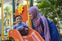 Молода азіатська мусульманка мати і дитина грають на ігровому майданчику — стокове фото