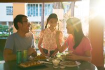 RELEASES Happy young asian family eating together in cafe — Stock Photo