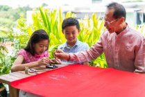 RELEASES Happy asian family together, grandfather and grandchildren drawing hieroglyphs — Stock Photo