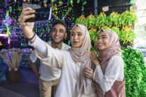 Un gruppo di amici si fa un selfie contro le decorazioni hari raya . — Foto stock