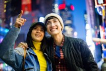 Young asian couple in time square, woman pointing up, New York, USA — Stock Photo