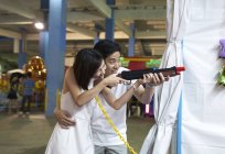 Paar spielt ein Ballerspiel auf einem Karneval, um Preise in Singapore zu gewinnen — Stockfoto