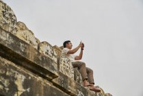 Joven tomando fotos en la pagoda Shwesandaw, Bagan, Myanmar - foto de stock