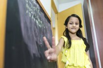 Jeune petite fille asiatique mignonne à l'école à côté du tableau de craie — Photo de stock